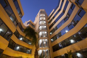A multi-story building with a central atrium, large windows, and a palm tree. - TURIM Presidente Hotel (Portimão)