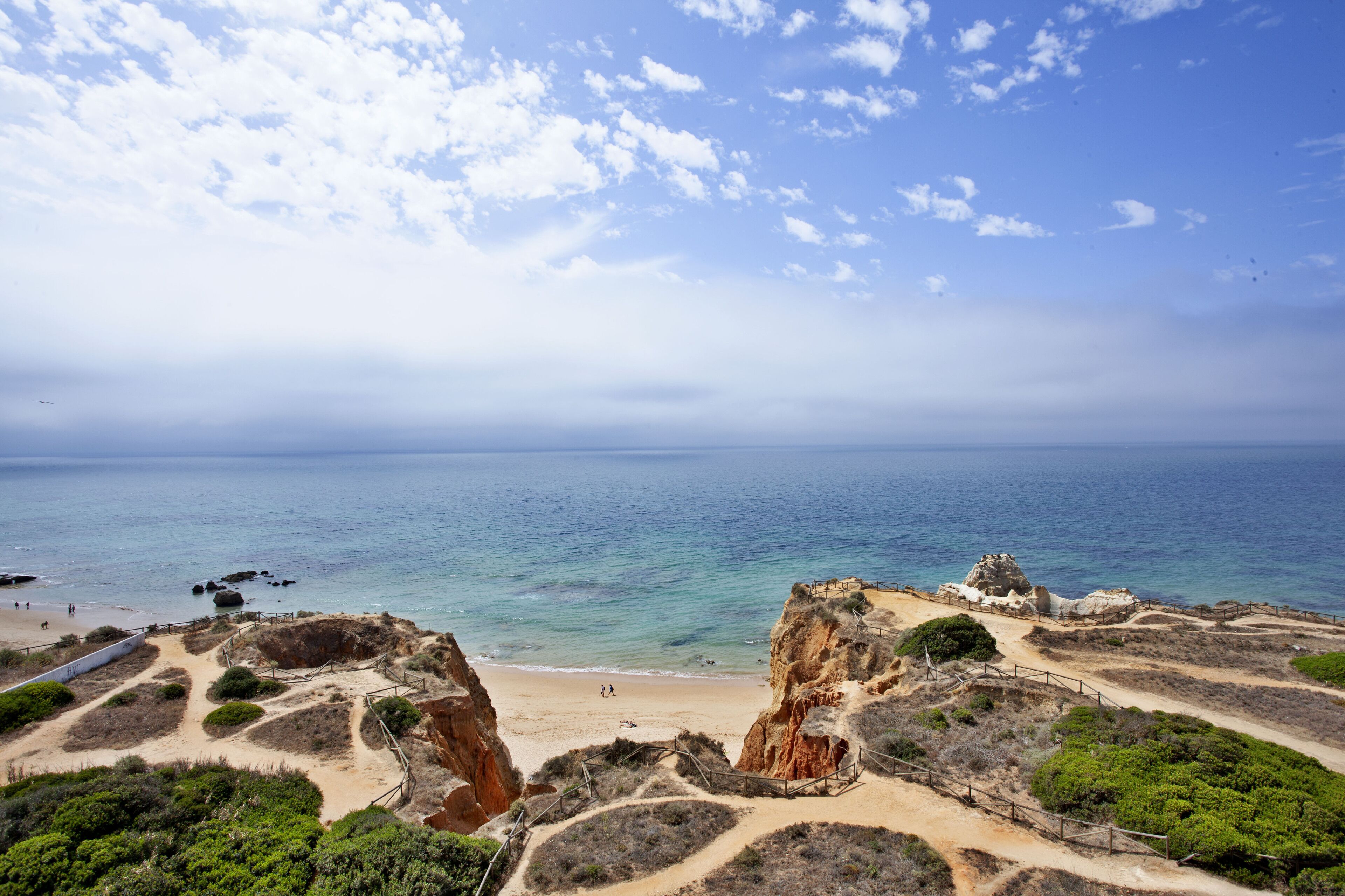 Eine Küstenlandschaft mit felsigem Gelände, einem Sandstrand und freiem Blick auf den Ozean.