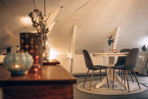 Uma área de refeições com uma mesa redonda, duas cadeiras e um vaso com flores.