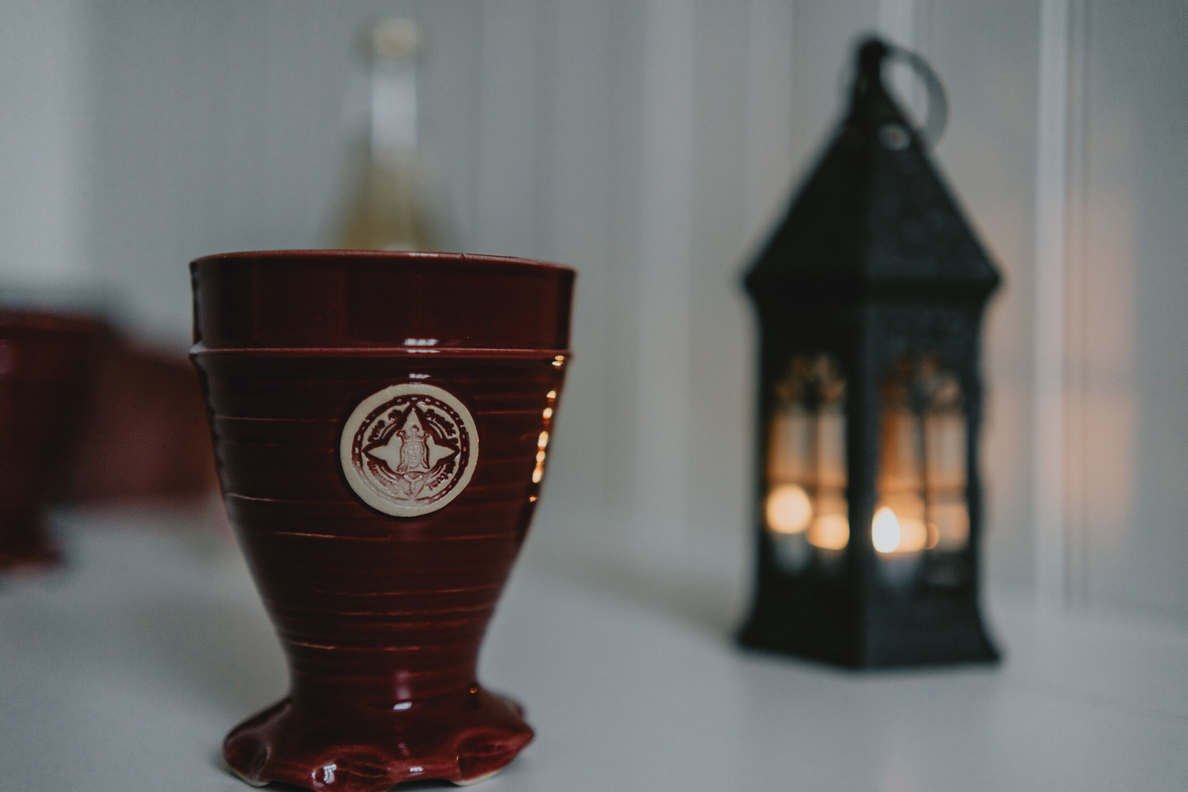 A red ceramic cup with a decorative emblem on a white surface.
