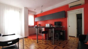 Une cuisine compacte avec un coin repas, comprenant un tabouret de bar, une petite table et un téléviseur.