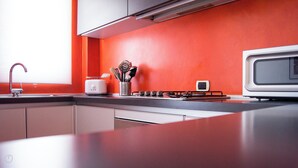 Une cuisine moderne avec un mur rouge, un grille-pain blanc, une cuisinière à gaz et un four à micro-ondes.