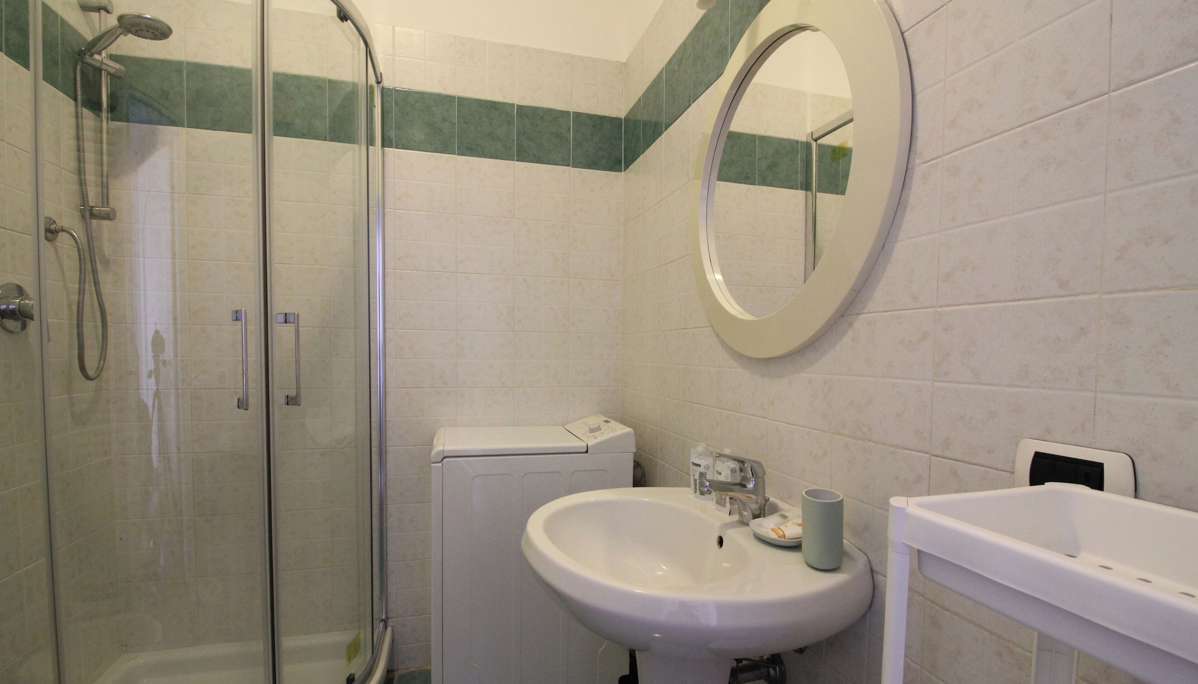 A bathroom with a glass-enclosed shower, a sink with a mirror, and a toilet.