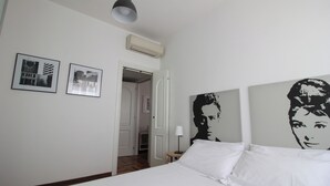 A hotel room with a bed, two framed pictures, a ceiling light, and a door leading to a hallway. - Italianway   - Lodi 78 (Milan)