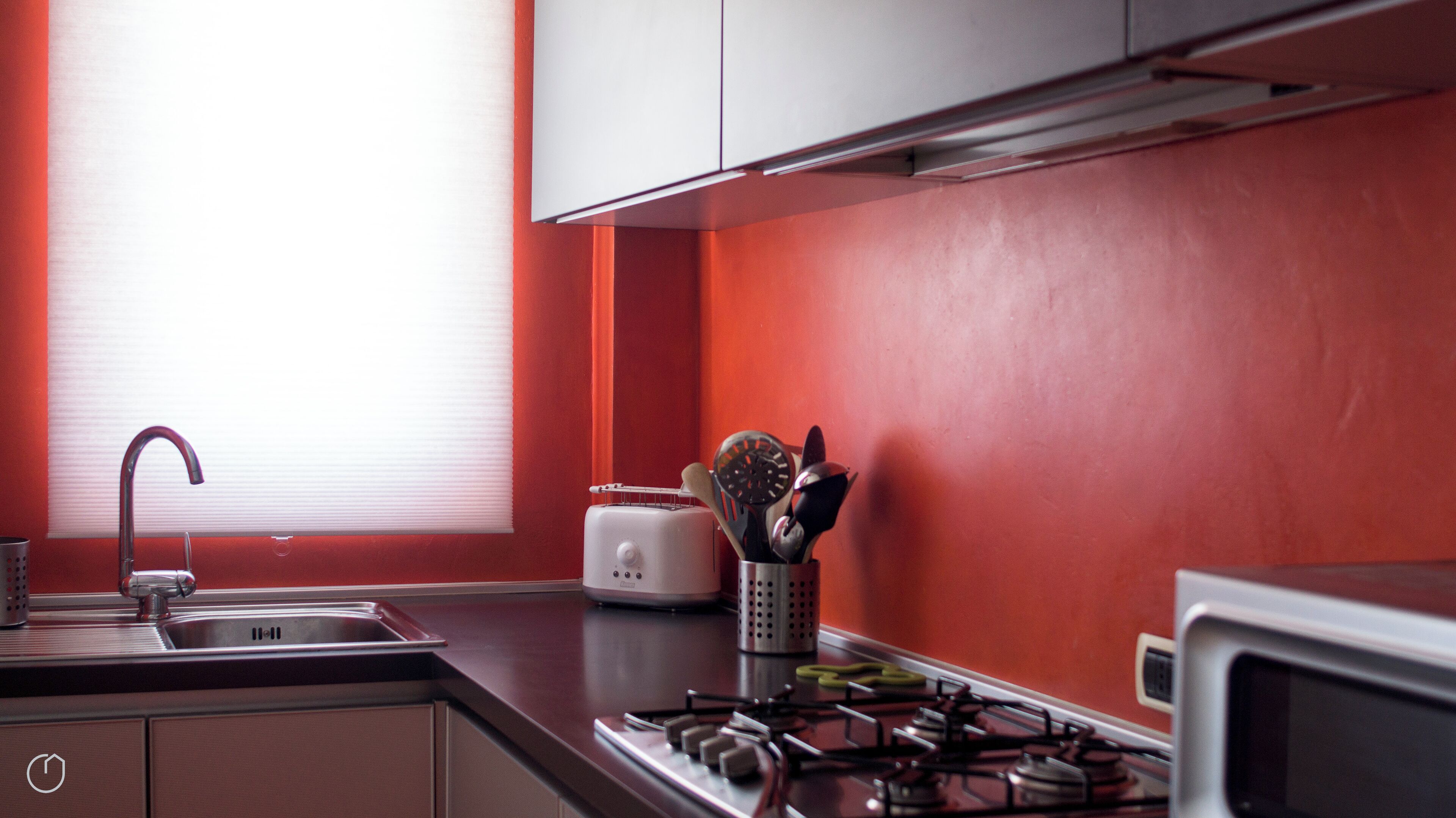 A kitchen with a modern design, featuring a stainless steel sink, a toaster, and a gas stove.