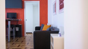Un salon comprenant un canapé, une table basse, une bibliothèque et un téléviseur.