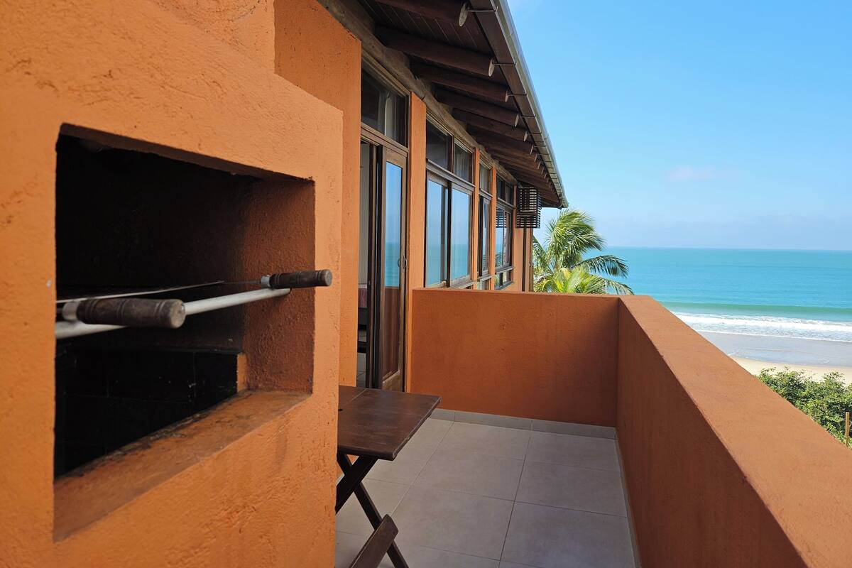 Ein Balkon mit Meerblick, einem Grill und einem Tisch.
