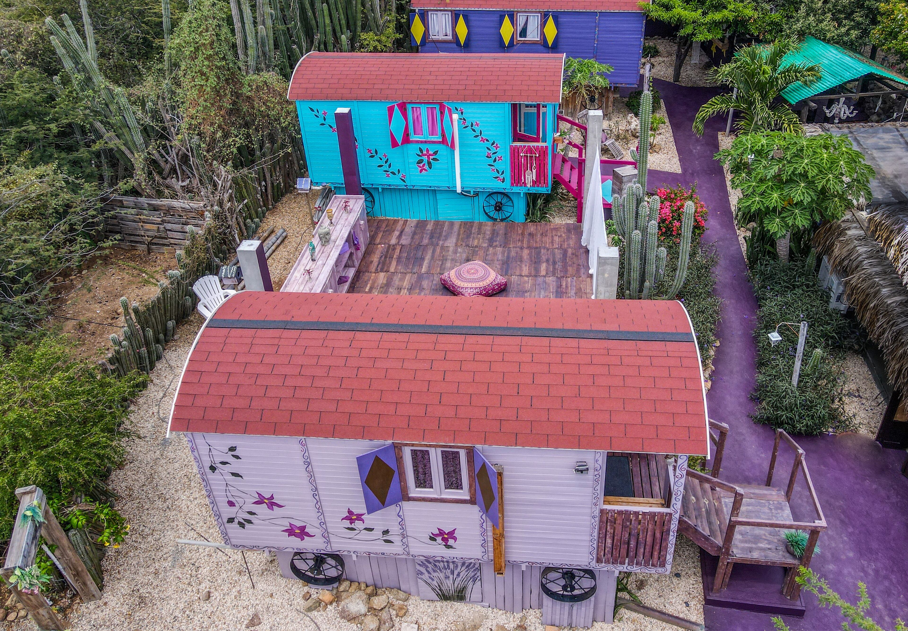 Une maison miniature avec un toit rouge, une façade bleue et un chemin violet menant à l’entrée.
