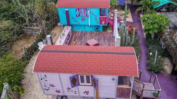 Une maison miniature avec un toit rouge, une façade bleue et un chemin violet menant à l’entrée.
