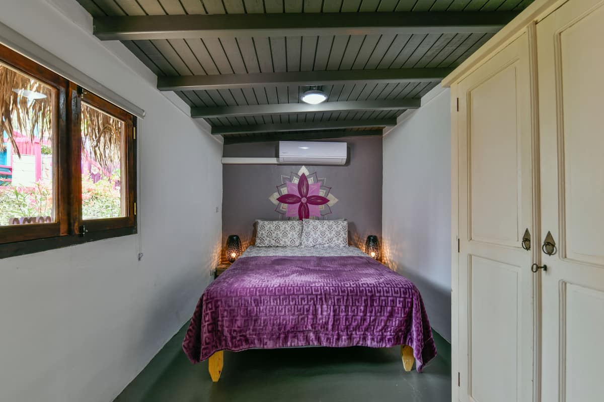 Un dormitorio con cama, aire acondicionado, ventana y puerta.