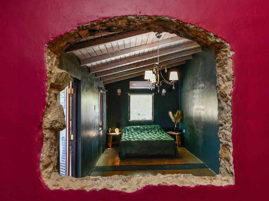 A bedroom with a bed, a chandelier, and a window.