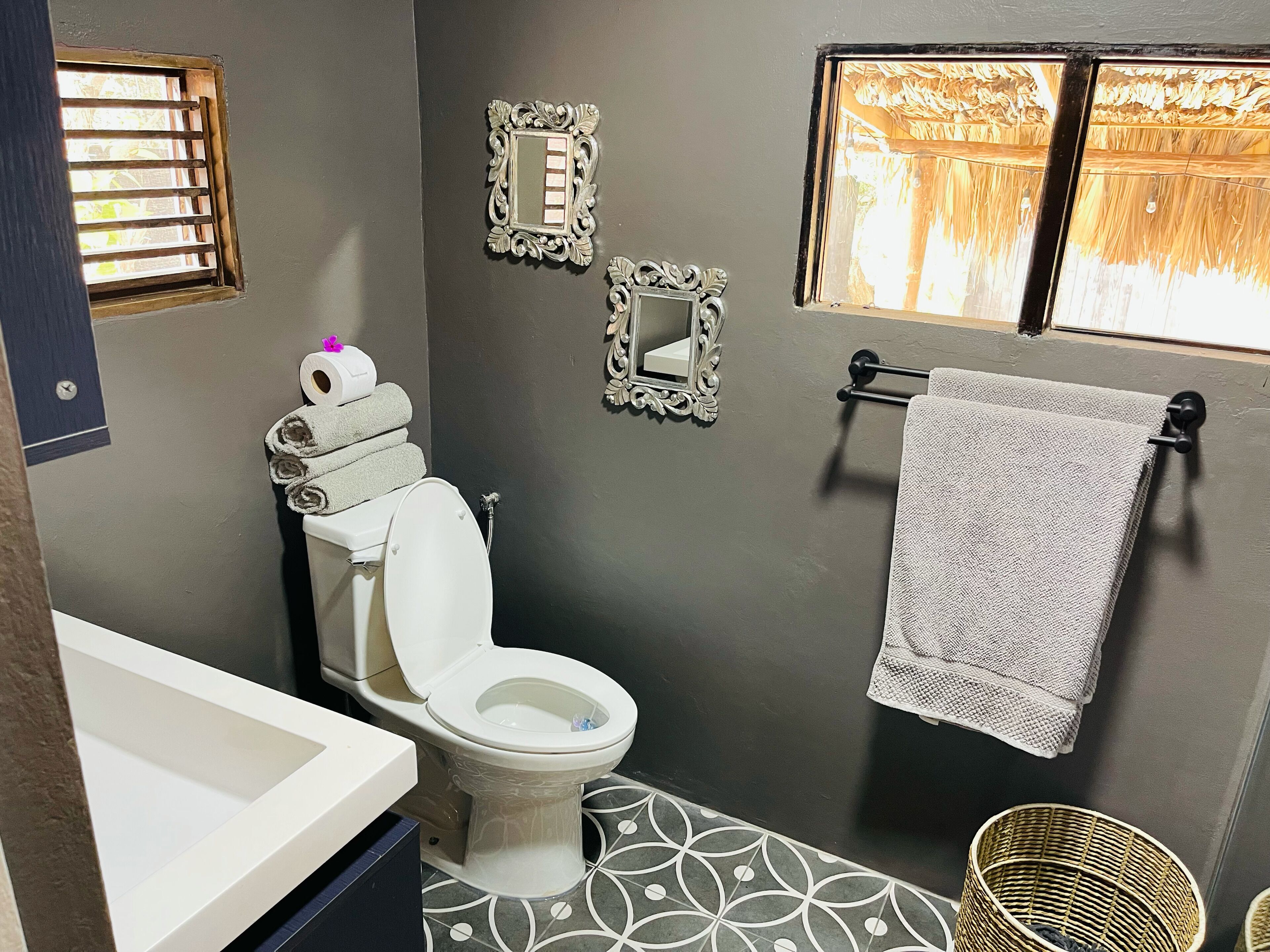 Un baño con inodoro, lavamanos y ventana con vistas a árboles.