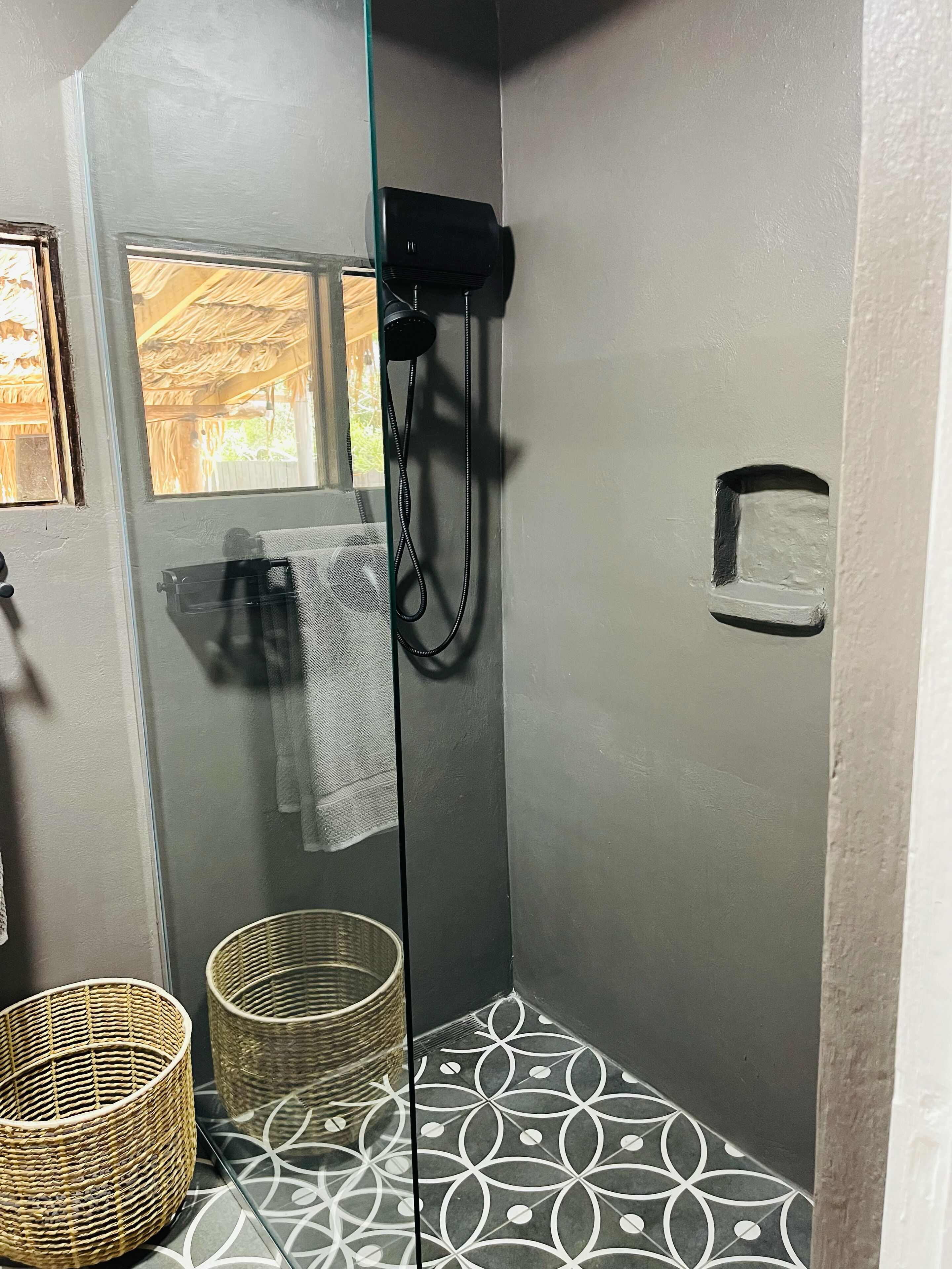 Un espace douche doté d’une porte en verre, d’un porte-serviettes et d’un panier en osier.