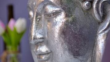 Nahaufnahme einer metallenen Buddha-Kopf-Skulptur mit strukturierter Oberfläche und glänzender Reflexion.