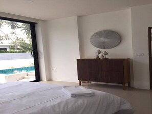 Un dormitorio moderno con una cama grande, un aparador de madera y vistas a una piscina.