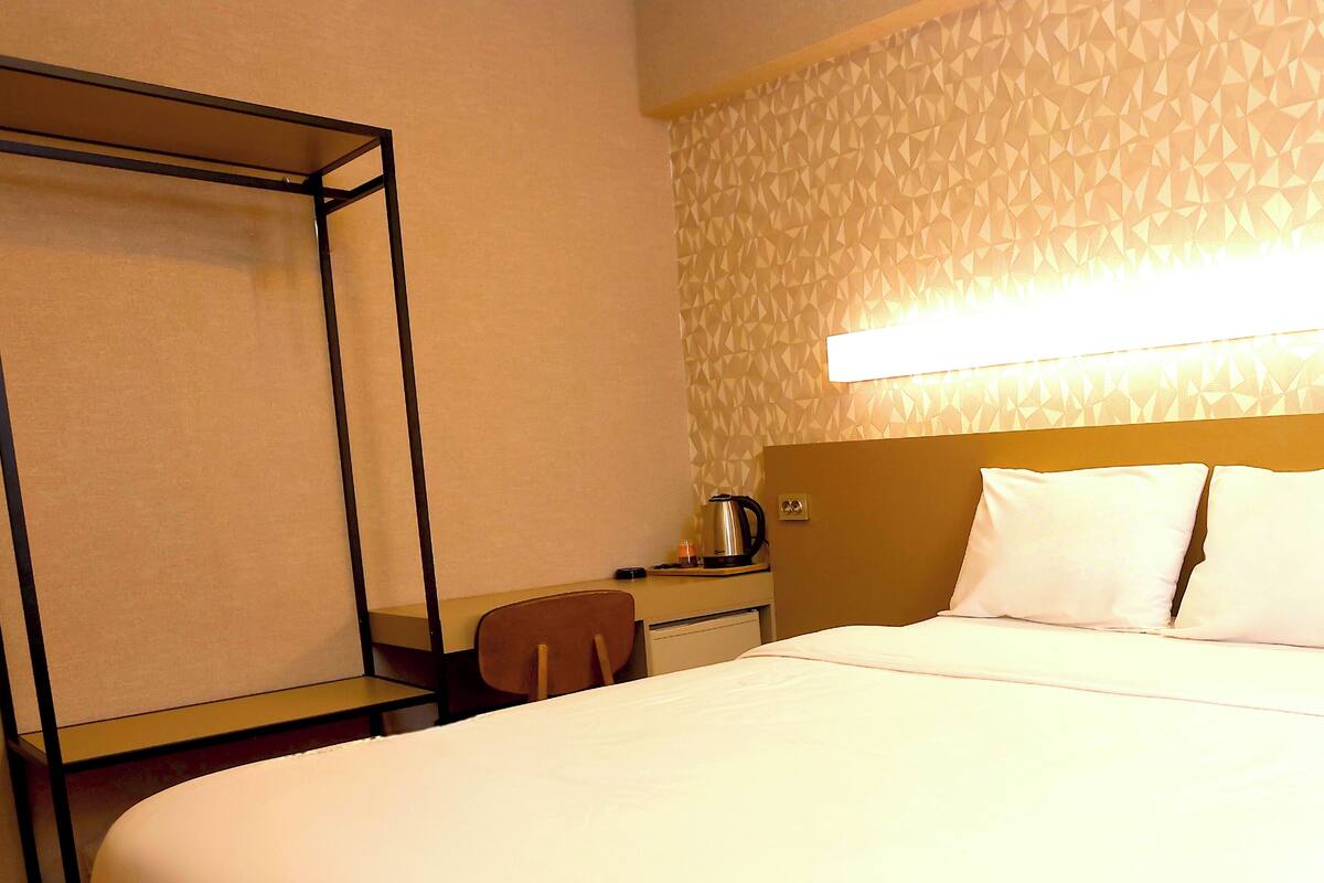 Una habitación de hotel con una cama grande, un escritorio con silla y una cafetera.