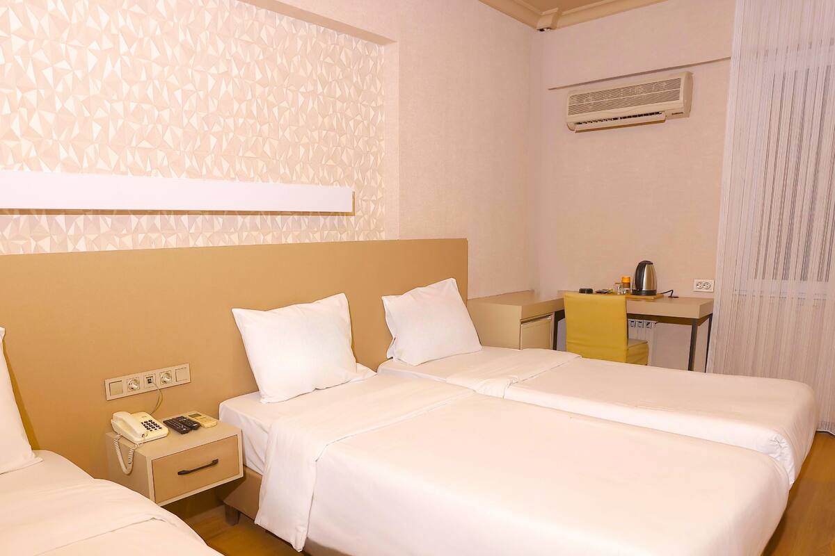 Una habitación de hotel con dos camas, un escritorio, un teléfono y aire acondicionado.