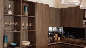 A modern kitchen with wooden cabinetry, a built-in stove, and a large window. - Villa Crawford (San Nicola Arcella)
