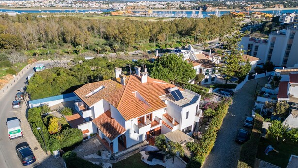 An aerial view of a residential area with a prominent house featuring a tiled roof, solar panels, and a well-maintained garden. - Urban Beach I (Portimão)