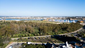 A coastal town with a marina, clear skies, and a mix of residential and commercial buildings. - Urban Beach I (Portimão)