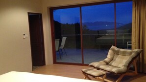 A hotel room with a large sliding glass door leading to a balcony with a view of the mountains. There is a single chair and a small table on the balcony. - 2 Bedroom Seaview Villa Laurenz (Koh Samui)
