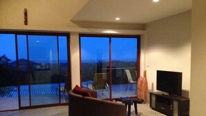 A modern living room with a large sliding glass door leading to a balcony, a sofa, a TV, and a small table. - 2 Bedroom Seaview Villa Laurenz (Koh Samui)
