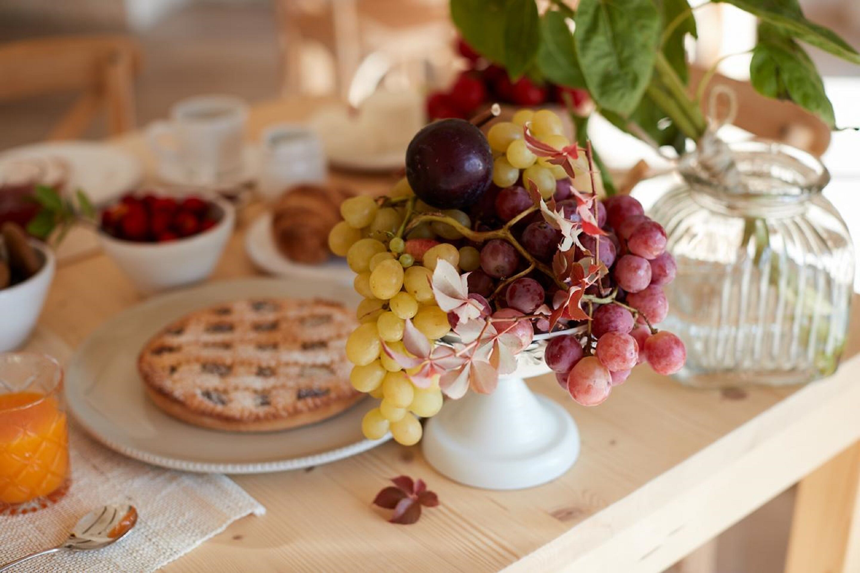 A breakfast setting with a fruit arrangement, a glass of orange juice, and a plate of muffins.
