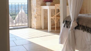 Un balcón con vistas a edificios, una mesa blanca con una silla y una cama con dosel.