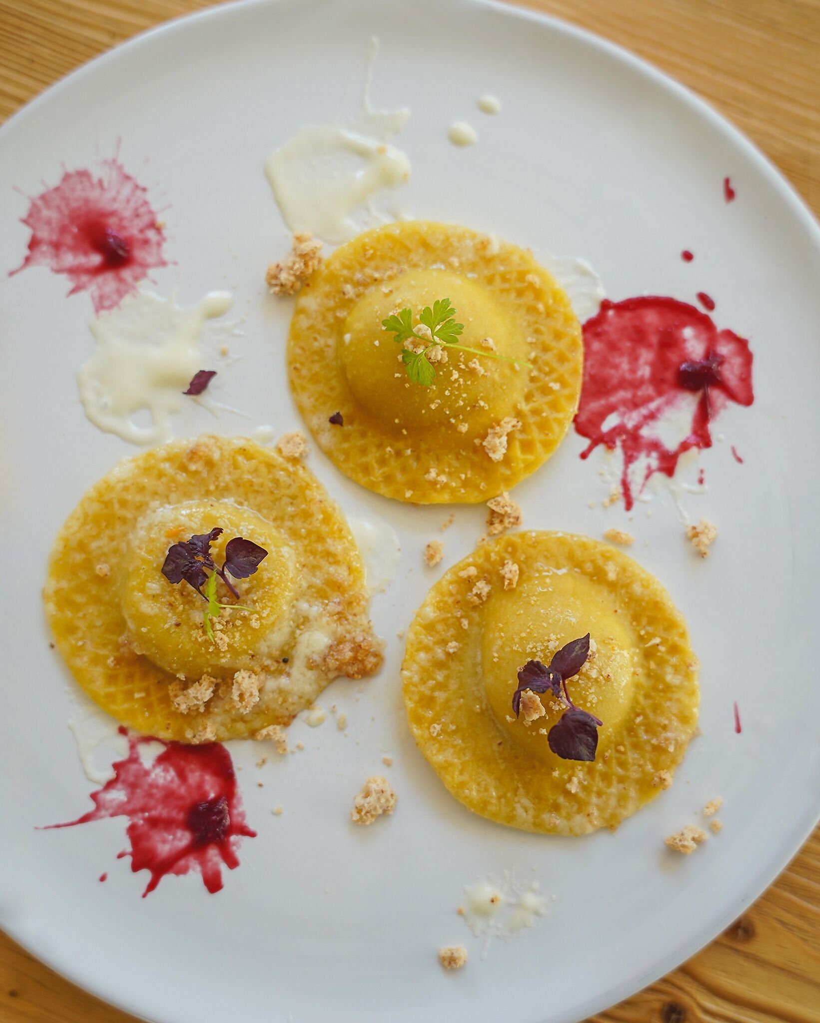 A plate of ravioli with a creamy sauce and garnishes.