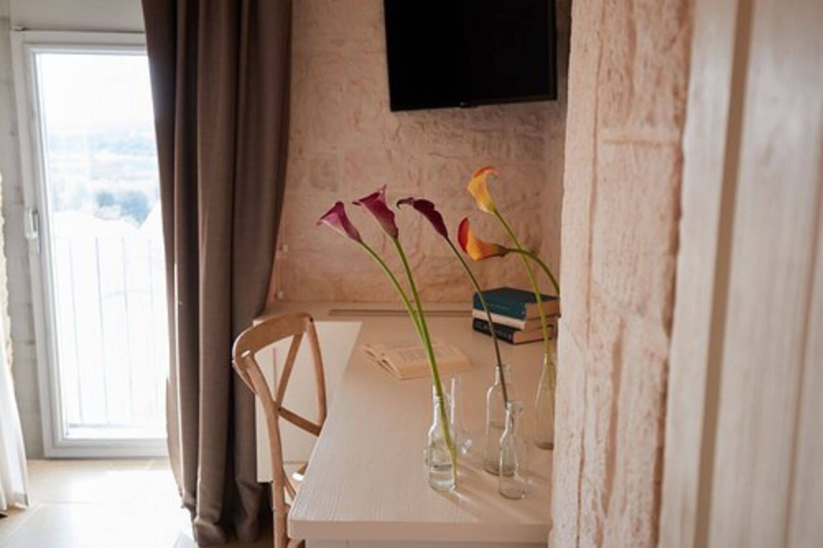 Een eettafel met transparante glazen vazen met bloemen, een boek en een menukaart.