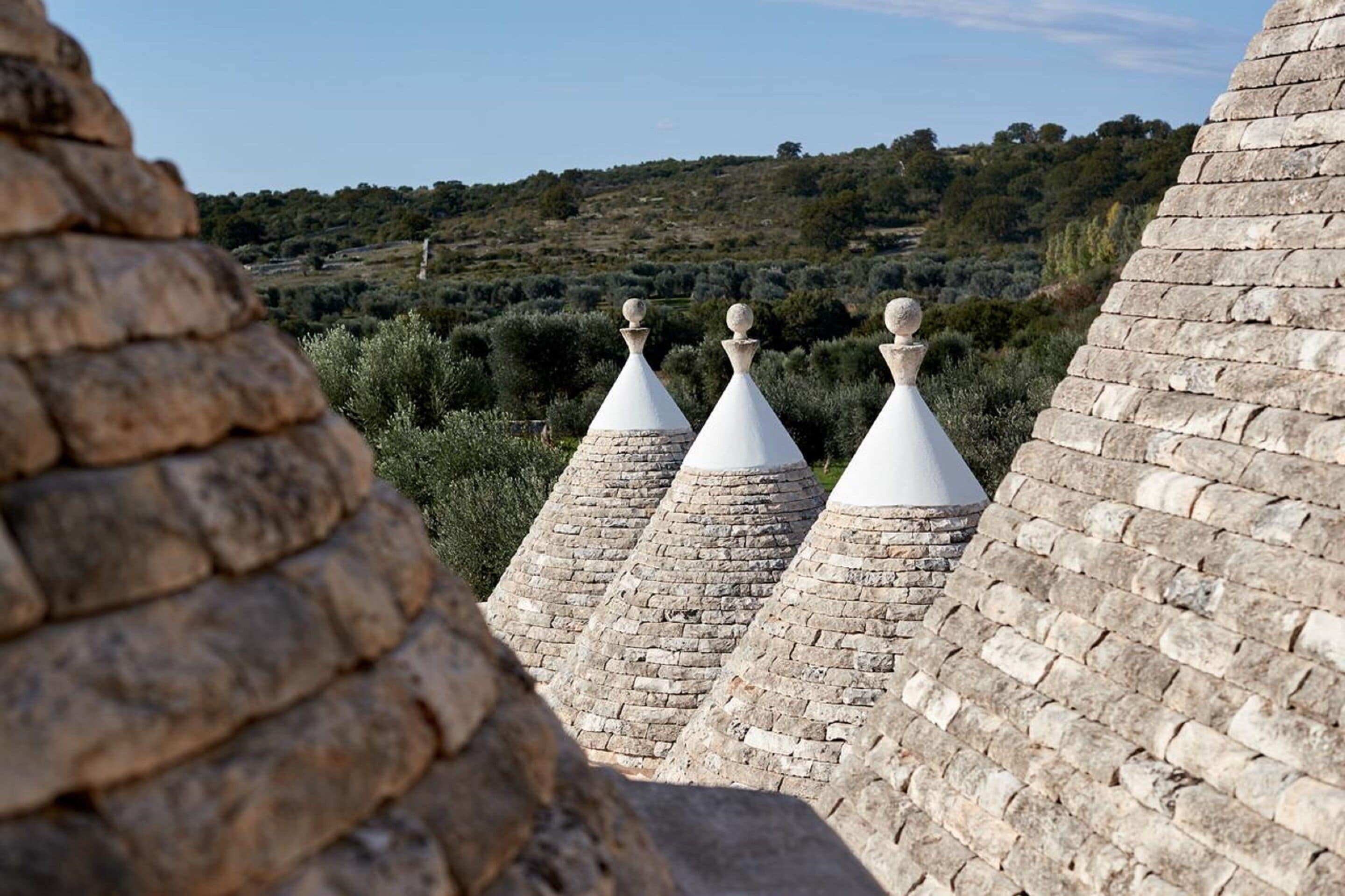 A stone building with conical roofs and a view of a hilly landscape.