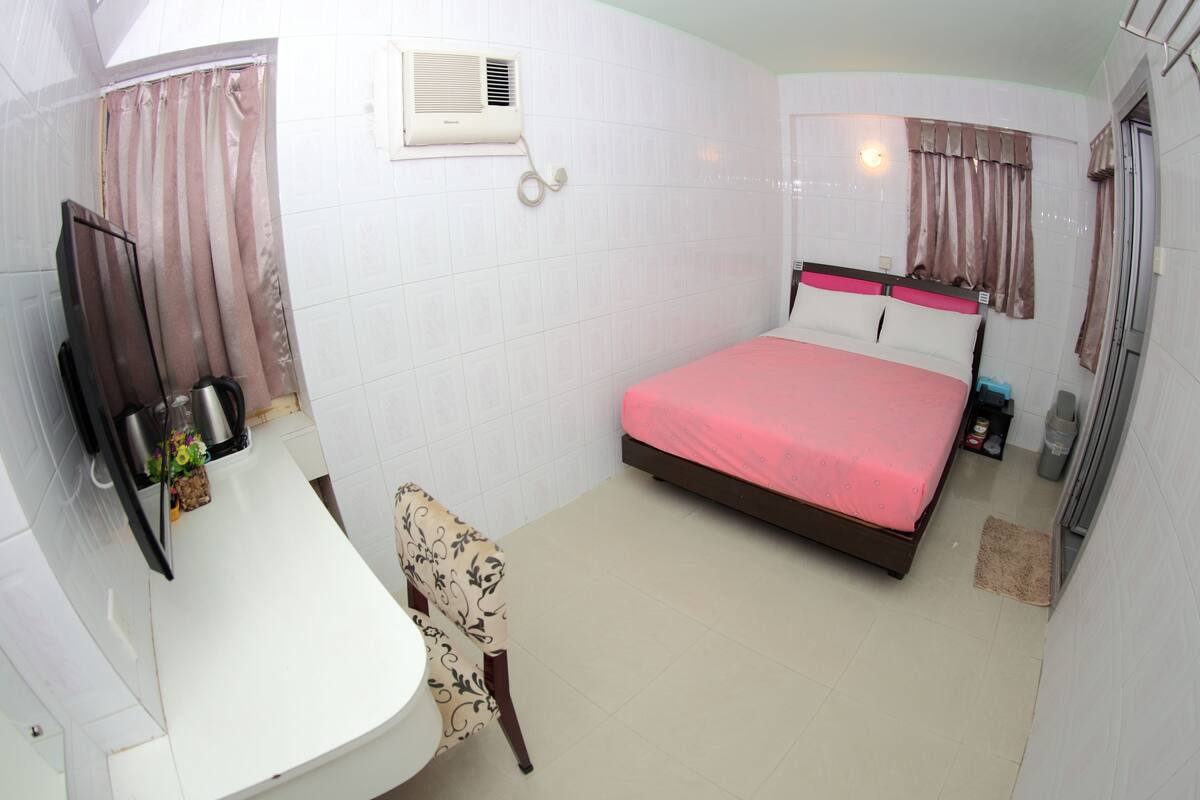 Una habitación de hotel con cama, una silla, escritorio, espejo y ventana con cortinas.