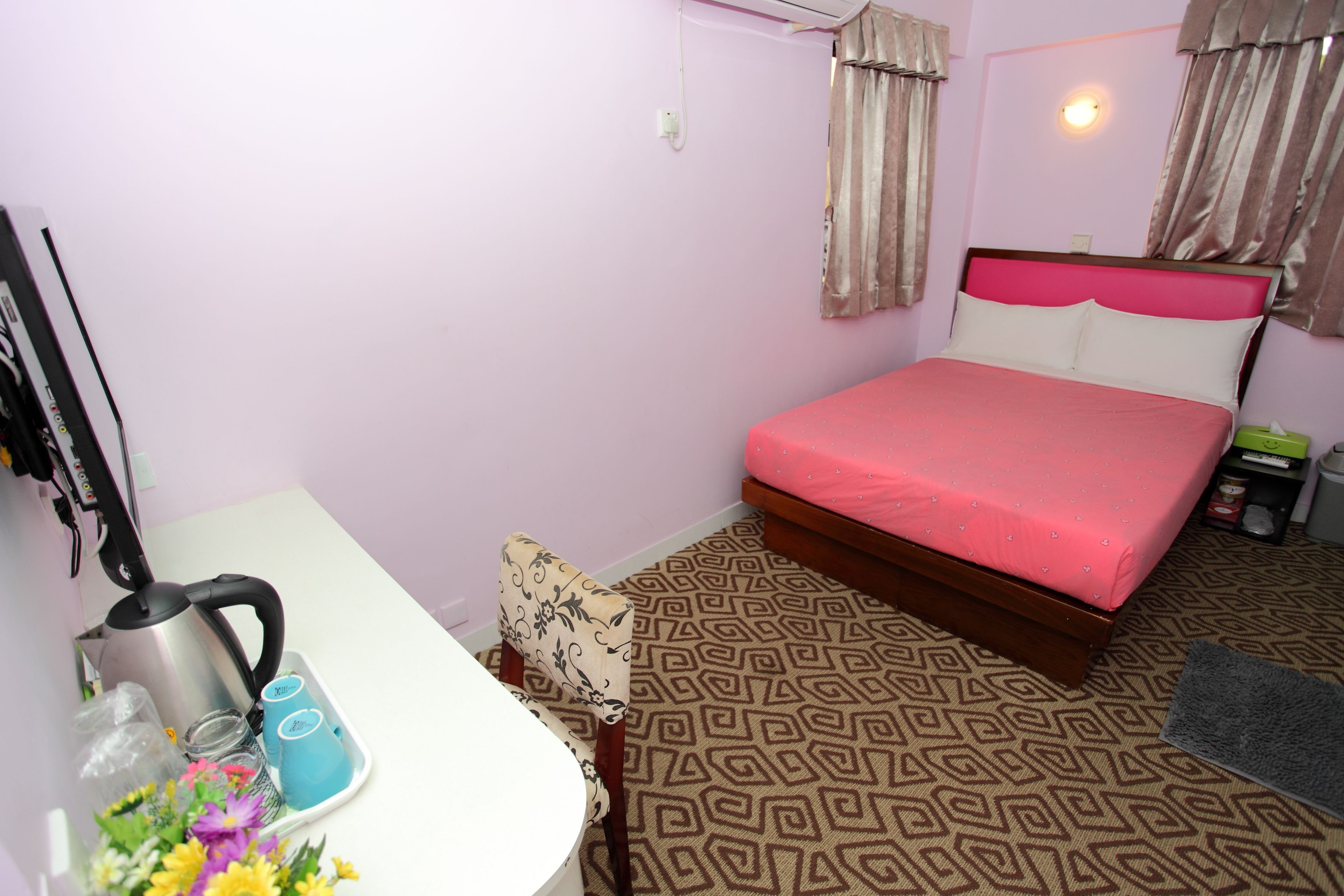 Un dormitorio con cama, escritorio, hervidor de agua y silla.