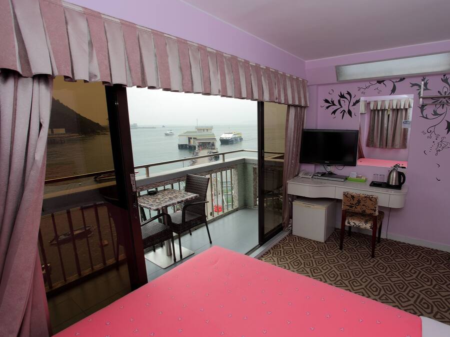 Ein Zimmer mit Bett, Schreibtisch, Stuhl, Fernseher und einem Balkon mit Meerblick.