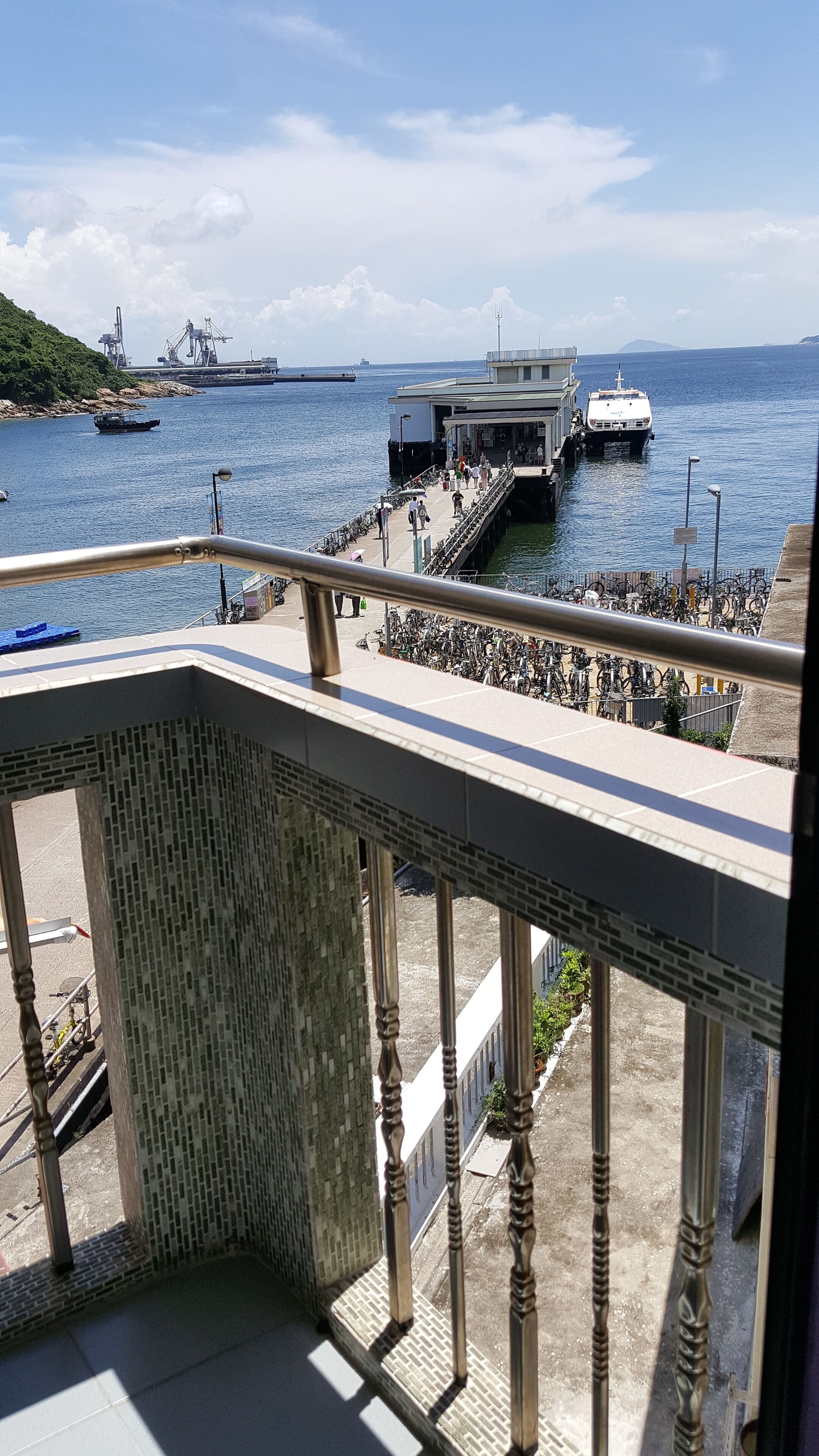 Un balcón con vista a un muelle, barcos y un barco lejano.