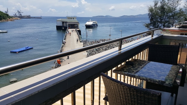 A waterfront promenade with a view of the sea, a dock with a boat, and a row of bicycles. - Man Lai Wah Resort (Lamma Island)