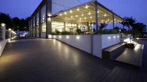 A modern building with a covered outdoor area, large windows, and a wooden deck. - Hotel Simeon (Polygyros)
