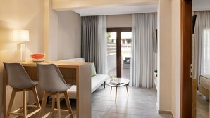 A modern hotel room with a wooden desk, two grey chairs, a small round table, a sofa, and a balcony with curtains. - Hotel Simeon (Polygyros)