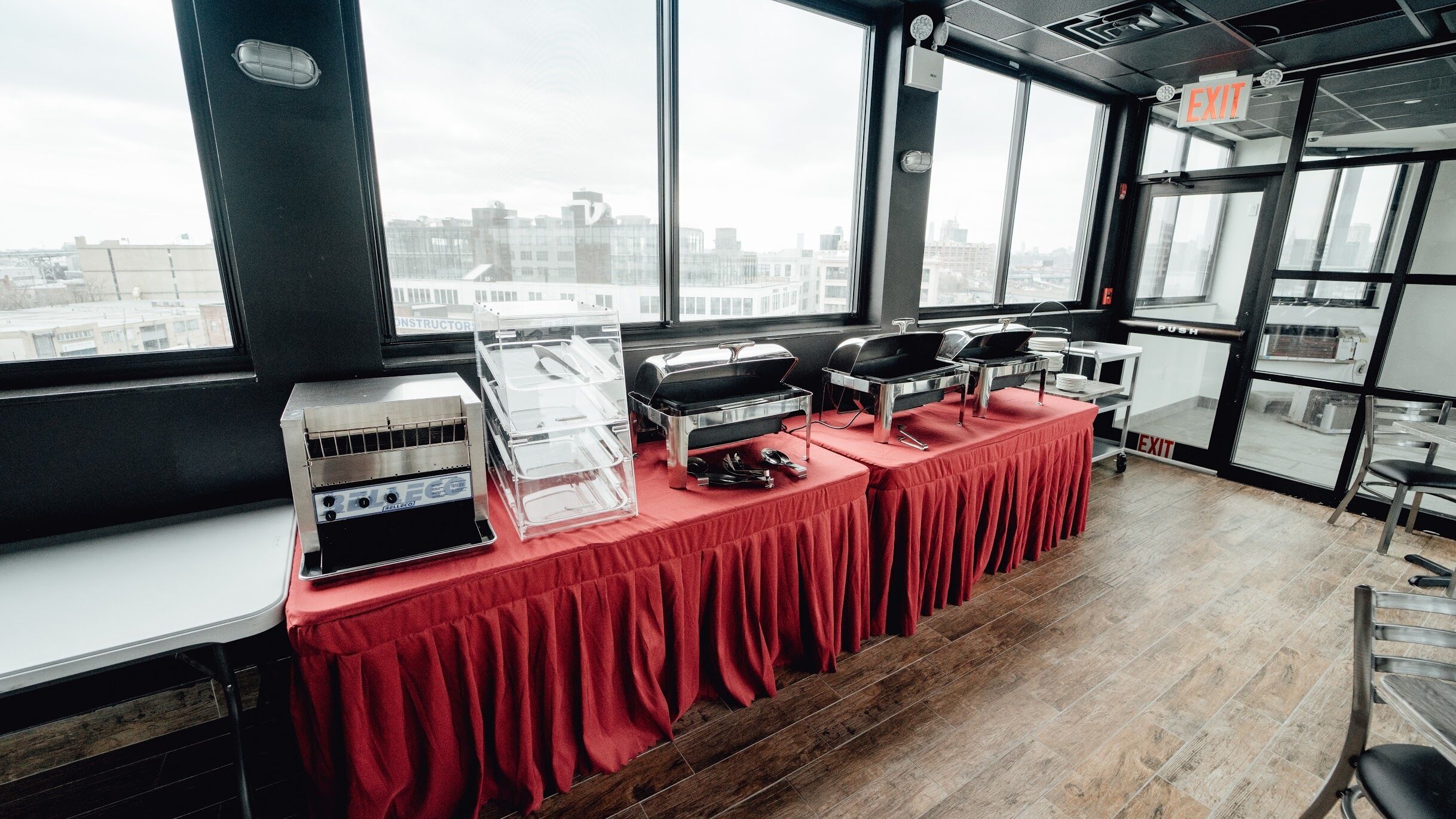 A buffet setup with multiple serving stations and a view of the city through large windows.