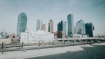 A cityscape with modern high-rise buildings, a train station, and a pedestrian walkway.