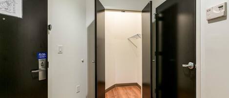 A narrow hallway with wooden flooring and black doors.