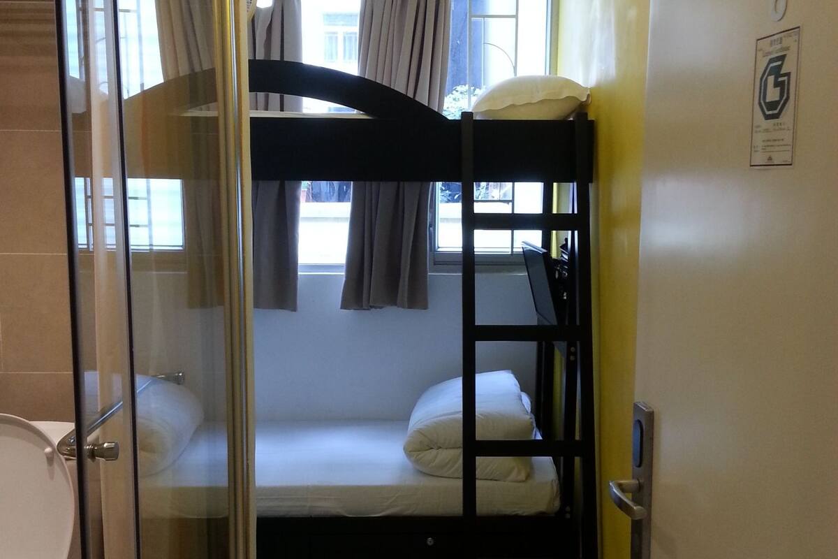A compact room with a bunk bed, a glass shower enclosure, and a toilet.