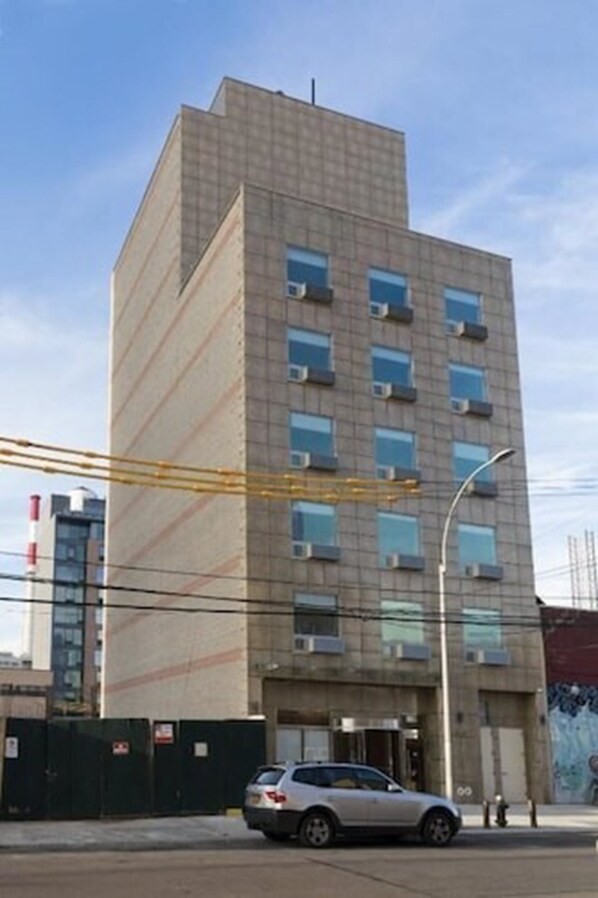 Un edificio de varios pisos con fachada plana, varias ventanas y un coche estacionado en frente.
