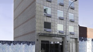 Ein modernes Gebäude mit ebener Fassade, zahlreichen Fenstern und einem Eingang im Erdgeschoss.