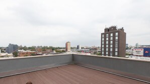 Eine Dachterrasse mit Blick auf eine Stadtlandschaft, darunter verschiedene Gebäude und ein klarer Himmel.