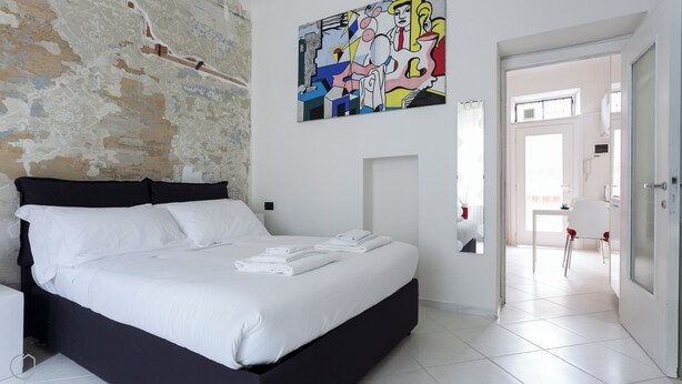 Een moderne slaapkamer met een groot bed, een witte muur met een muurschildering en uitzicht op de badkamer.