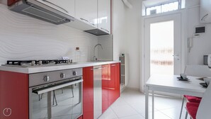 Een moderne keuken met een gasfornuis, oven en rode kastjes.