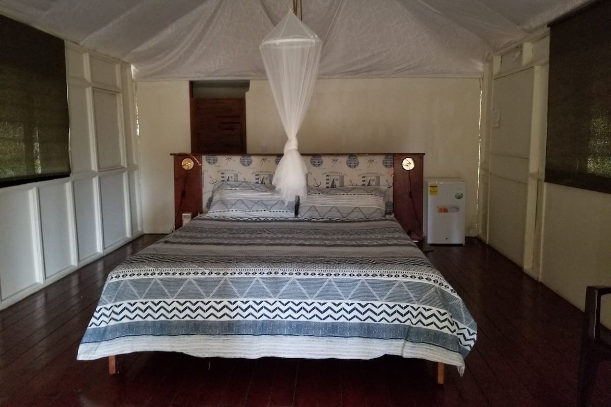 Een bed met hemel, een nachtkastje en een klok aan de muur.