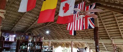 A bar area with flags of Belgium, Canada, and the USA hanging from the ceiling.