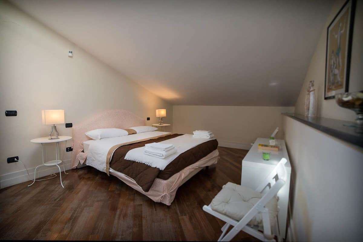 A bedroom with a bed, bedside tables, a desk, and a chair.